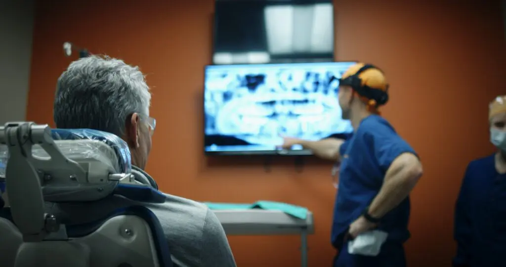 patient in dental chair looking at x-rays